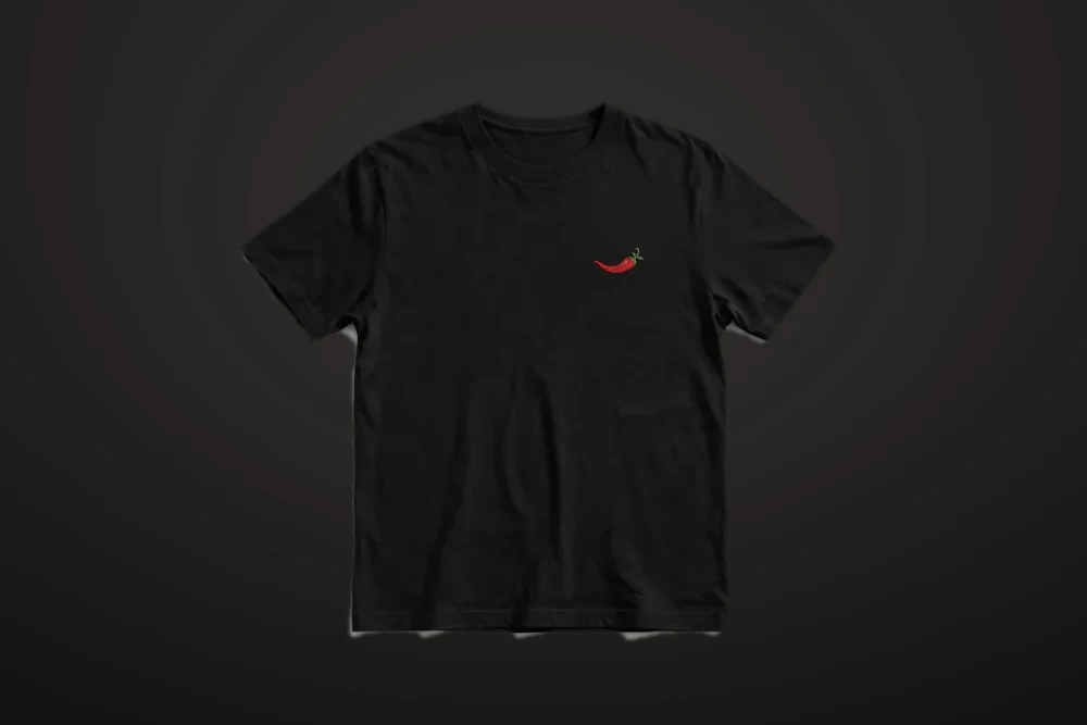 Black crew-neck t-shirt with the small red chili emblem embroidered on the left chest, dark studio